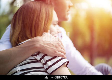 Un jeune homme embrasse une femme. Assis serrant dans le parc Banque D'Images