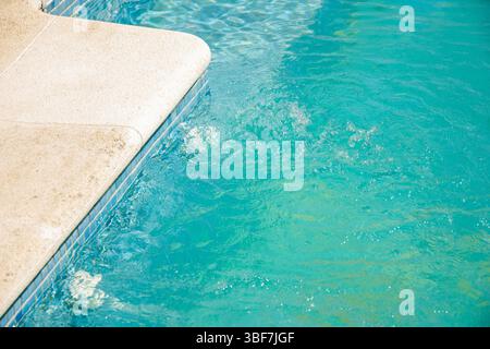 rafraîchissant eau de piscine turquoise éclaboussant contre le bord de pierre, concept de fond d'été Banque D'Images