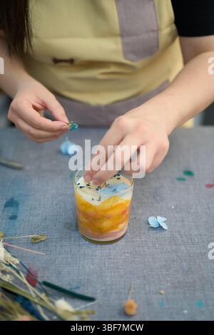 Fabricant de bougies Ajouter des fleurs séchées aux bougies faites à la main : artisanat et créativité Banque D'Images