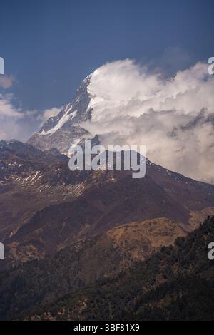 Une vue imprenable sur le sommet enneigé de l'Annapurna Sud quand les nuages serrent doucement les montagnes dans le grand Himalaya au Népal. Banque D'Images