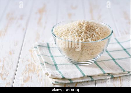 Riz basmati blanc bio dans un bol en verre transparent sur une table lumineuse, mise au point sélective. Banque D'Images