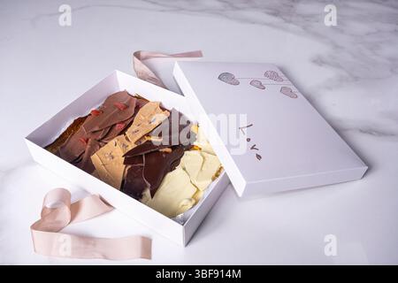 Une boîte blanche ouverte avec des pépites de chocolat assorties. Banque D'Images