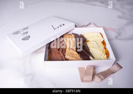 Une boîte blanche ouverte avec des pépites de chocolat assorties et le mot amour. Banque D'Images
