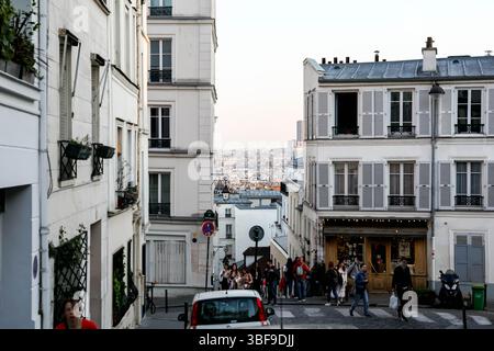 Une vue panoramique sur une rue animée et en pente de Montmartre, Paris, bordée de bâtiments traditionnels et de boutiques, révélant un aperçu du dist Banque D'Images