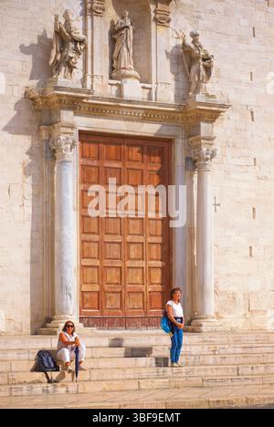 Touristes sur les marches à l'extérieur de la cathédrale de Bari - Cathédrale de Saint Sabinus - Duomo di Bari ou Cattedrale di San Sabino) est la cathédrale de Bari, dans les Pouilles, dans le sud de l'Italie. La cathédrale est le siège de l'archevêque de Bari-Bitonto, comme il l'était auparavant pour les archevêques, anciens évêques, de Bari. Il est dédié à Saint Sabinus, évêque de Canosa, dont les reliques ont été apportées ici au IXe siècle. Elle est plus ancienne que la basilique Saint-Nicolas des Pouilles, bien que moins célèbre que celle-ci. Bari, Pouilles, Italie Banque D'Images
