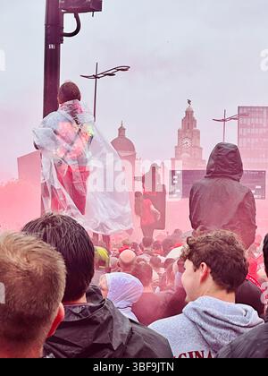 Des foules se rassemblent sur le Strand pendant la parade de Liverpool, des filles sur des lampadaires avec de la fumée rouge et Liver Building en arrière-plan, le 25 mai 2025 Banque D'Images