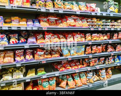 Kiel, Allemagne - 28. Mai 2025 : étagères pleines de croustilles colorées, pop-corn et autres collations dans un supermarché à Kiel, en Allemagne Banque D'Images