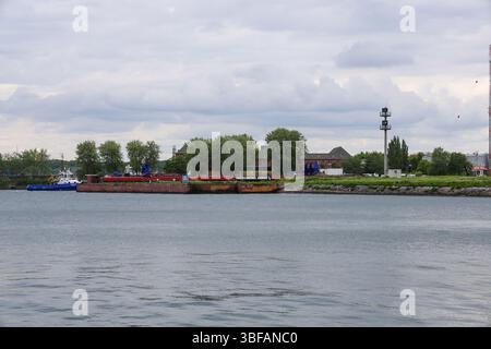 Kiel, Allemagne - 28. Mai 2025 : chaland d'assistance de remorqueur dans le canal de Kiel, près d'une tour de contrôle, par temps nuageux Banque D'Images