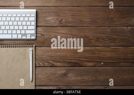 Nature morte de l'espace de travail de bureau avec fournitures. Vieux bureau en bois plat avec clavier d'ordinateur blanc, stylo et cahier. Vue de dessus du concept d'entreprise. Vint Banque D'Images