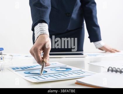 Femme d'affaires debout près du bureau et analysant les graphiques financiers. Directeur d'entreprise réussi dans le costume d'affaires. Gros plan main de femme avec stylo. B Banque D'Images