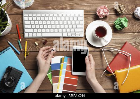 Concepteur Web choisissant des couleurs à partir de nuances au bureau en bois. Bureau vue de dessus avec clavier d'ordinateur et papeterie. Conception de l'interface utilisateur o Banque D'Images