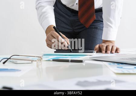 Homme d'affaires se tenant près du bureau et analysant les diagrammes financiers. Directeur d'entreprise réussi en costume et cravate d'affaires. Gros plan main homme avec un Banque D'Images