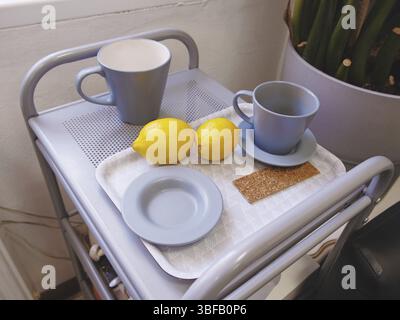 Mugs en céramique bleus et citrons sur table de service, au bureau Banque D'Images