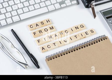 Trésorerie provenant des activités de financement concept avec lettres. Nature morte du lieu de travail de bureau avec fournitures. Surface blanche plate avec clavier d'ordinateur et c Banque D'Images