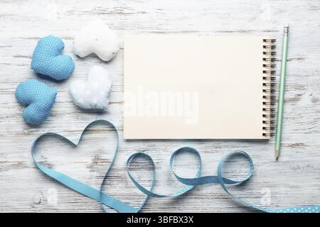 Composition élégante à plat avec des coeurs en tissu bleu et blanc faits à la main. Ouvrir le carnet de croquis avec stylo sur la table en bois vintage. Saint Valentin congr Banque D'Images