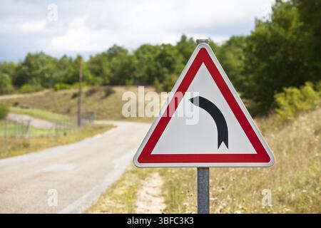 Le trafic triangulaire signe indiquant la route tourne à gauche sur un chemin rural background Banque D'Images