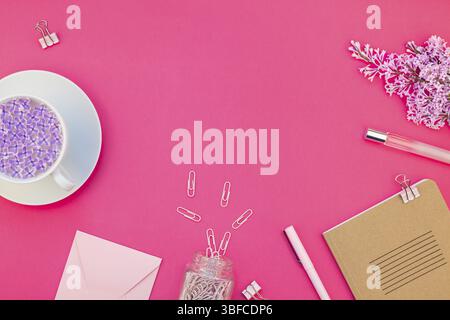 Vue de dessus de la création de l'espace de travail de mise à plat design style bureau Fournitures de bureau et une tasse de thé avec l'exemplaire de l'espace sur un fond de papier de couleur rose vif mini Banque D'Images
