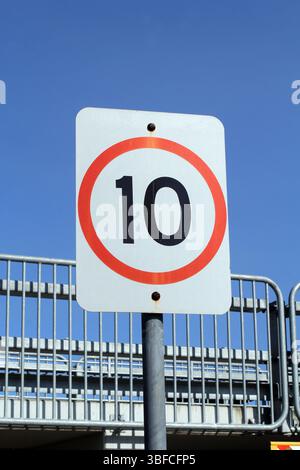 10 km par heure limite de vitesse panneau routier monté sur un poteau avec une clôture métallique et le ciel en arrière-plan Banque D'Images