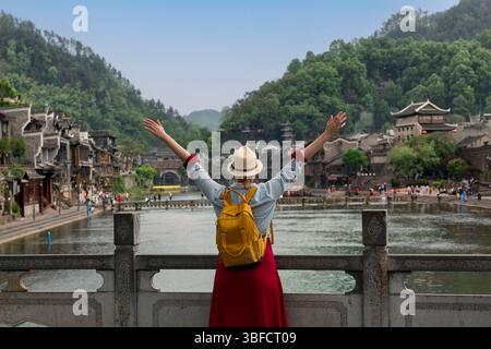 Jeune femme touriste regardant le beau paysage de la ville antique de Feng Huang, la célèbre destination touristique de la province du Hunan, en Chine Banque D'Images