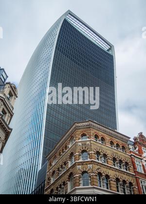 Walkie Talkie bâtiment à Londres, haut gratte-ciel vu d'en bas avec fond de ciel nuageux. Contraste entre l'architecture ancienne et la structure de verre moderne Banque D'Images