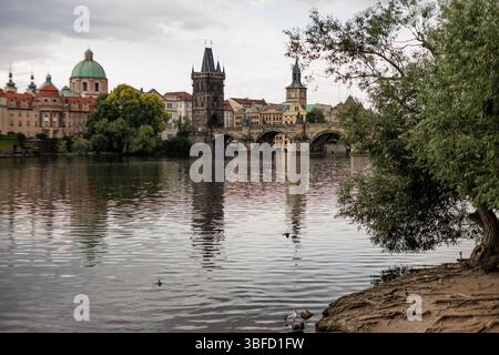 Prague, république tchèque - 23 juillet 2024 : pont Charles réfléchissant sur la rivière vltava à prague sous ciel nuageux Banque D'Images