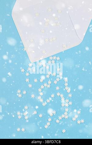 Vue de dessus de la création d'hiver. châssis mise à plat Modèle Maquette Concept fait de petits flocons blancs sur fond bleu pastel enveloppe lettre copie espace minim Banque D'Images