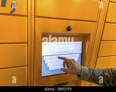 Homme utilisant Amazon Locker dans le centre commercial, point de ramassage orange pour les marchandises par correspondance avec le logo de la marque Amazon. Photographie mobile. Lyon, France - F Banque D'Images