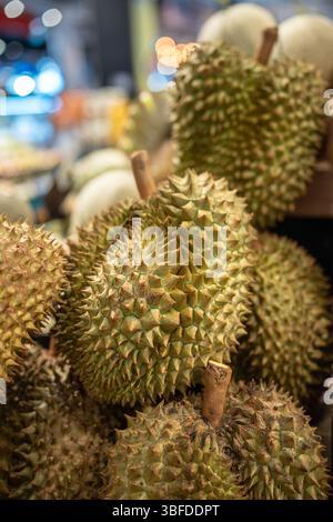Durian fruits sur l'étagère du supermarché prêt pour la sélection du client, gros plan. Des stands d'épicerie en Asie Banque D'Images