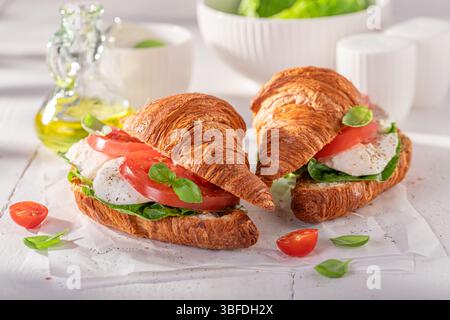 Croissant français maison et doré avec mozzarella et tomates. Croissants comme sandwich avec fromage et tomates. Banque D'Images