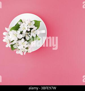Télévision créative concept laïcs Vue de dessus de tasse à café et fleurs de pommier blanc sur fond rose avec copie espace dans un style minimaliste, modèle f Banque D'Images