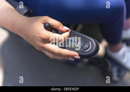 Gros plan de la main d'une femme actionnant le joystick de son fauteuil roulant électrique, mettant en valeur la mobilité et la liberté Banque D'Images