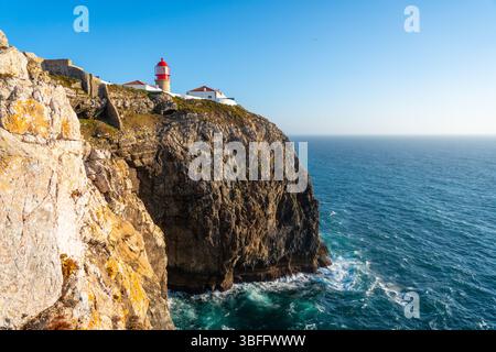 Le phare de Cabo da Roca avec son sommet rouge distinctif est perché sur une haute falaise accidentée surplombant le vaste océan Atlantique et la côte courbe Banque D'Images