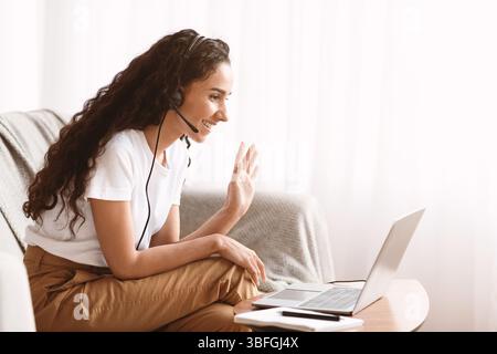 Une jeune femme heureuse avec un casque qui s'ouvre sur l'écran d'un ordinateur portable Banque D'Images