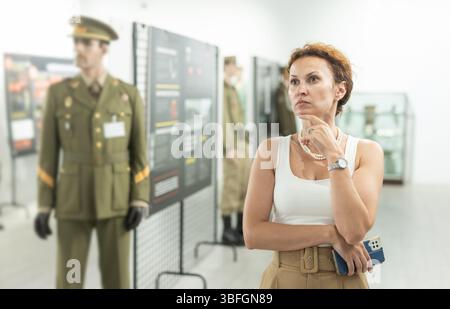 Femme d'âge moyen regardant des expositions dans le musée militaire Banque D'Images