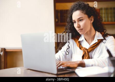 Femme assise au bureau, en utilisant l'ordinateur et la dactylographie Banque D'Images