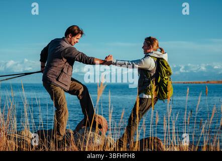 Touristes homme et femme tenant les mains debout sur des pierres sur fond de lac Banque D'Images