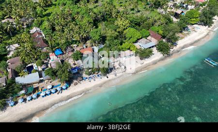 Détendez-vous sur une plage tropicale ensoleillée bordée de palmiers et de parasols colorés, à quelques pas des eaux cristallines accueillantes et douces Banque D'Images
