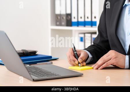 Homme d'affaires écriture à la main sur la note postale au bureau Banque D'Images