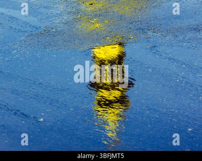 Bouée jaune reflétée sur l'eau bleue avec de petites ondulations créant une image abstraite aux couleurs contrastées Banque D'Images