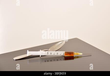 Seringue de médicament et héroïne cuite avec cuillère sur une table Banque D'Images