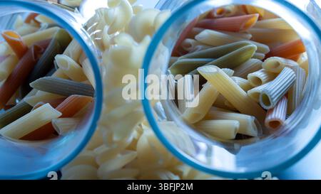 pâtes penne tricolores sèches et fusilli dans des bocaux en verre, gros plan, ingrédients alimentaires Banque D'Images
