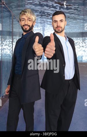 Deux hommes d'affaires confiants en costumes donnant les pouces vers le haut et souriant à la caméra Banque D'Images