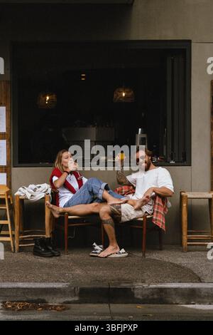 Jeune couple se trouvant dans un café de rue, Byron Bay, Australie Banque D'Images
