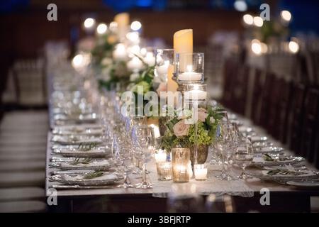Élégante table de réception éclairée aux chandelles avec fleurs et verrerie Banque D'Images