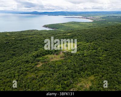 Vue aérienne de la forêt verdoyante et du littoral en Bulgarie. Pré ouvert et ruines antiques visibles parmi les arbres. Paysage pittoresque de la mer Noire Banque D'Images