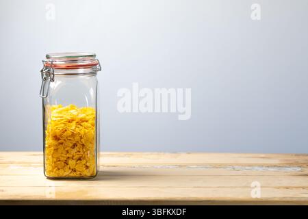 Pot en verre rempli de cornflakes placés sur le côté gauche de la table en bois rustique, studio shot avec espace de copie sur la droite pour le texte ou la conception Banque D'Images