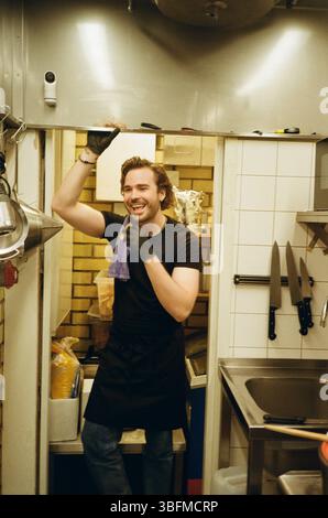 Homme heureux debout dans la cuisine du restaurant Banque D'Images