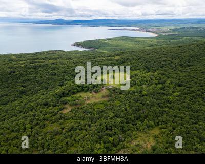 Vue aérienne de la forêt verdoyante et du littoral en Bulgarie. Pré ouvert et ruines antiques visibles parmi les arbres. Paysage pittoresque de la mer Noire Banque D'Images