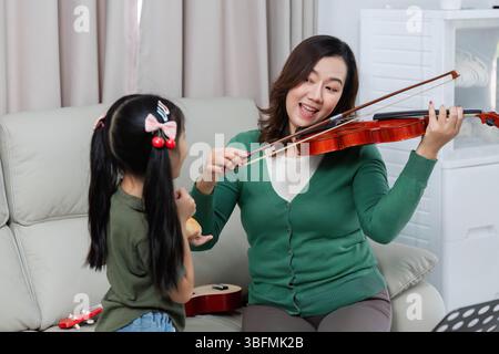 Interaction musicale. Mère et fille aiment jouer du violon ensemble à la maison. Banque D'Images