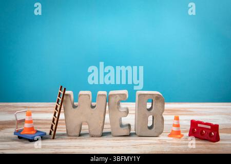 Concept WEB. Lettres d'alphabet en béton sur un fond blanc en bois et bleu. Banque D'Images